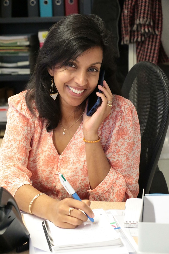 Une collaboratrice au bureau utilise la téléphonie IP et prend des notes, illustrant le support téléphonique et informatique pour les TPE et PME
